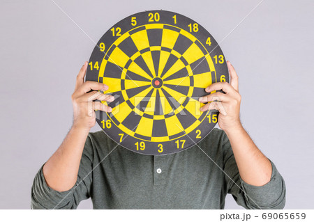 People holding yellow Dartboard and hide his face. Studio shot i People holding yellow Dartboard and hide his face. Studio shot i 69065659