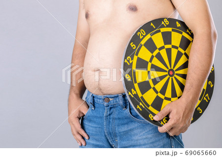 Fat people holding round yellow dartboard beside his belly posit Fat people holding round yellow dartboard beside his belly posit 69065660
