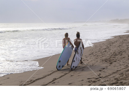 Two surfers couple go on the ocean beach with longboards in hand. 69065807