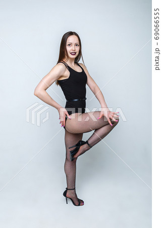 Beautiful girl dancer in black clothes posing on a light background. The girl has long hair. 69066555