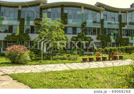 Facade of the academic buildings of The international College, covered  hanging gardens    of climbing plants in the suburbs of Dilijan 69068268