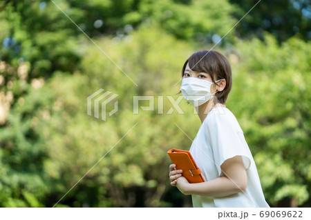 新型コロナ肺炎の中手帳を片手に歩く若い女性 新型コロナ肺炎の中手帳を片手に歩く若い女性 69069622