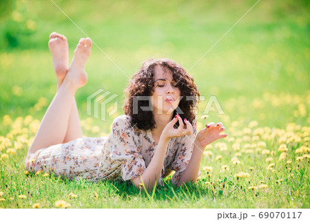 Young attractive woman with curly long hair posing in spring blooming garden, apple trees Young attractive woman with curly long hair posing in spring blooming garden, apple trees 69070117