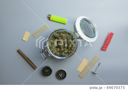 Top view of cannabis smoking stuff. Marijuana and paper on gray background Top view of cannabis smoking stuff. Marijuana and paper on gray background 69070373
