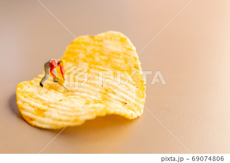Miniature people Worker are working with potato chips Miniature people Worker are working with potato chips 69074806