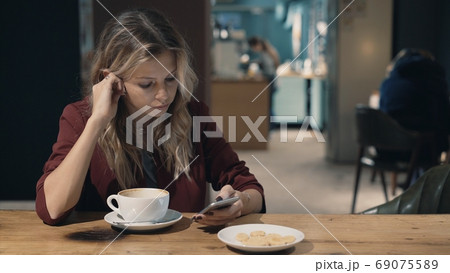 Attractive woman in cafe browsing the Internet using smart phone and waiting some meeting with Attractive woman in cafe browsing the Internet using smart phone and waiting some meeting with 69075589