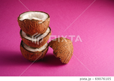 Stacked coconut fruits on pink purple plain background Stacked coconut fruits on pink purple plain background 69076105