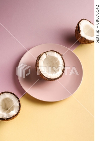 Coconut half in plate with nut fruits on cream yellow and pink Coconut half in plate with nut fruits on cream yellow and pink 69076142