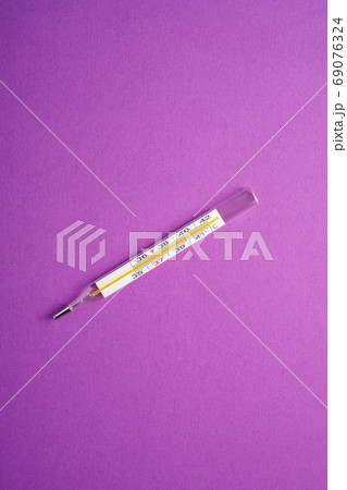 Analog thermometer on violet purple background Analog thermometer on violet purple background 69076324
