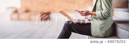 young woman with laptop sitting on the stairs 69079202