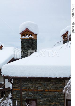 Chimney and chalet roof covered with deep snow 69079203