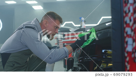 Male technician washing car headlight 69079293