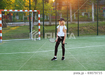 Girl with a racket in her hands on the sports field. Girl with a racket in her hands on the sports field. 69079735