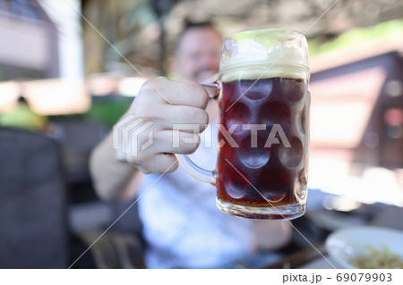 Man is holding glass of foamy glass with beer 69079903