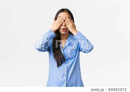 Surprised and excited cute asian girl in blue pajamas close eyes and open mouth thrilled, awaiting for surprise gift, waiting for sign, standing in jammies over white background Surprised and excited cute asian girl in blue pajamas close eyes and open mouth thrilled, awaiting for surprise gift, waiting for sign, standing in jammies over white background 69082072