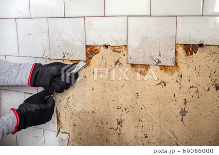 Renovation. Old dirty wall tiles. Worker with a crowbar Renovation. Old dirty wall tiles. Worker with a crowbar 69086000