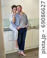 Husband and wife are at home in the kitchen. 69086627