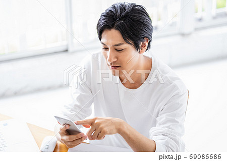 明るい室内でスマホを操作する若い男性 69086686