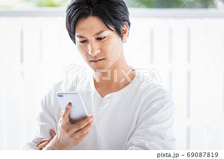 真剣な眼差しでスマホを見ている若い男性 69087819
