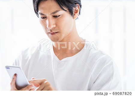 真剣な眼差しでスマホを見ている若い男性 69087820