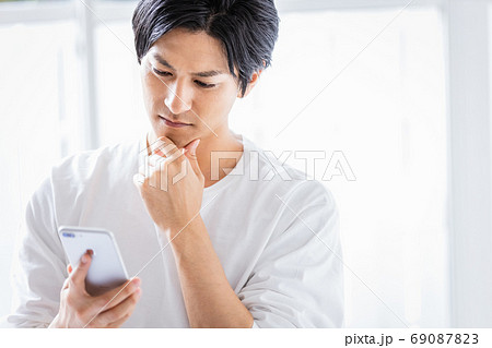 真剣な眼差しでスマホを見ている若い男性 69087823