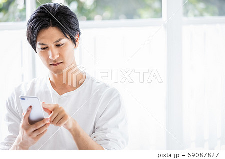 真剣な眼差しでスマホを操作している若い男性 真剣な眼差しでスマホを操作している若い男性 69087827