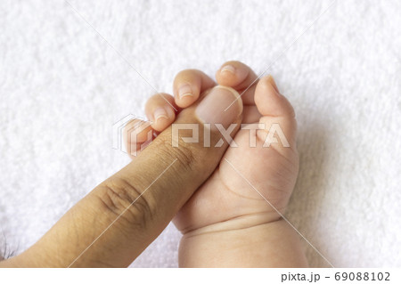 30代の父親の指を握りしめる 生後二ヶ月の赤ちゃんの手の写真素材