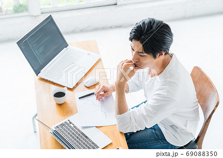 明るい室内でデスクワークをしている若い男性 明るい室内でデスクワークをしている若い男性 69088350