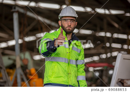 Portrait of male Engineer standing with confident against machine environment in factory Portrait of male Engineer standing with confident against machine environment in factory 69088653