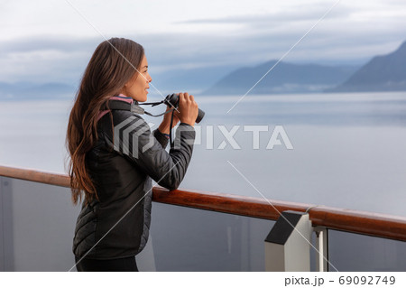 Alaska cruise woman on whale watching boat excursion tour looking at wildlife with binoculars. Tourist at inside passage Glacier Bay destination on travel ship vacation enjoying scenic cruising. 69092749