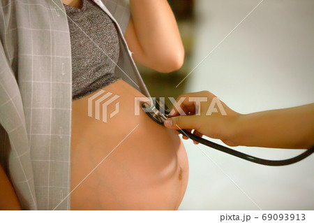 close up of a doctor holding stethoscope on pregnant women	 69093913