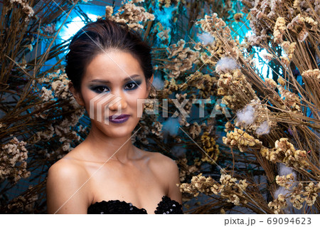 Asian woman in Fur cloth in bush variety of flowers posing on ba Asian woman in Fur cloth in bush variety of flowers posing on ba 69094623