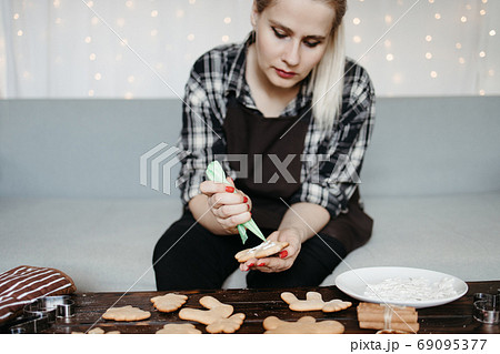 Woman decorating homemade gingerbread cookies Woman decorating homemade gingerbread cookies 69095377