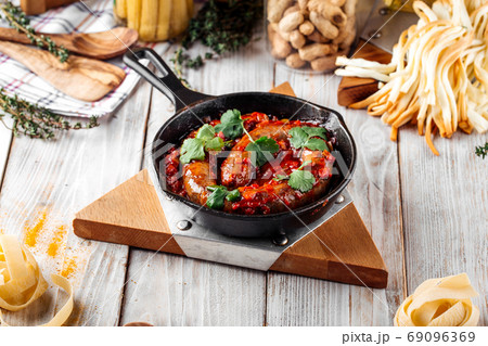 Large sausage in tomato sauce in cast iron pan Large sausage in tomato sauce in cast iron pan 69096369