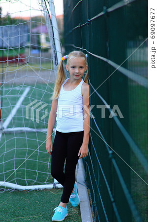 A girl posing near a football goal on a sports field. A girl posing near a football goal on a sports field. 69097677