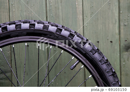 Bicycle Wheel Against an Old Shed Door 69103150
