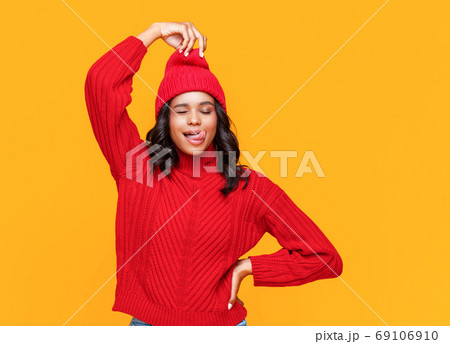 Playful ethnic woman pulling hat. 69106910