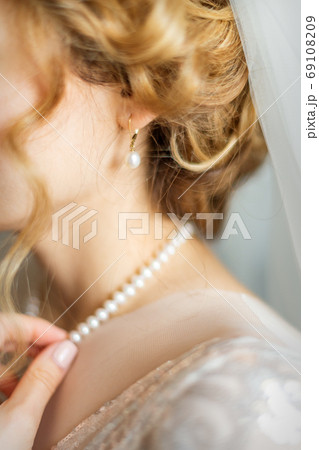Bride dresses necklace before wedding 69108209