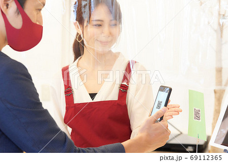感染症対策をした店でQRコードを案内する店員と読み取るお客 感染症対策をした店でQRコードを案内する店員と読み取るお客 69112365