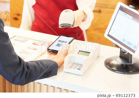 スマホに表示したバーコードを読み取る店員 69112373