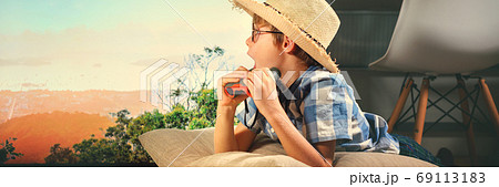 Boy in straw hat lying down and imitating scouting Boy in straw hat lying down and imitating scouting 69113183