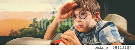 Boy in straw hat lying down and imitating scouting Boy in straw hat lying down and imitating scouting 69113184