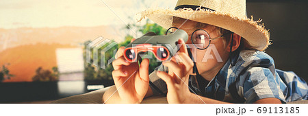 Boy in straw hat lying down and imitating scouting Boy in straw hat lying down and imitating scouting 69113185