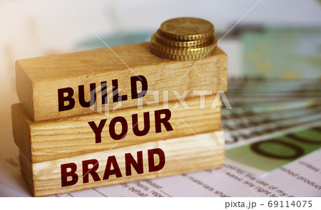 Wooden blocks form the text 'build your brend' on 100 Euro currency bills and coins background. Branding and marketing business concept Wooden blocks form the text 'build your brend' on 100 Euro currency bills and coins background. Branding and marketing business concept 69114075