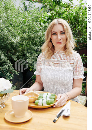 Pretty woman eating spring rolls 69114360