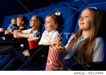 Happy friends eating popcorn in cinema. Happy friends eating popcorn in cinema. 69114940