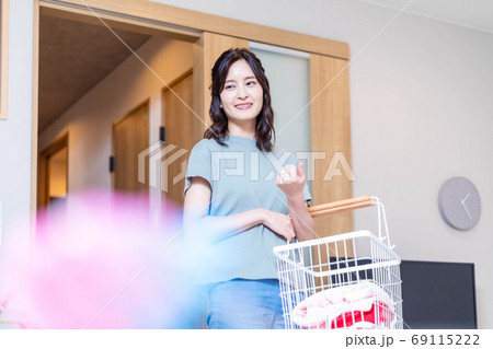 自宅で洗濯物を運ぶ若い主婦 自宅で洗濯物を運ぶ若い主婦 69115222
