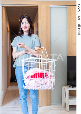 自宅で洗濯物を運ぶ若い主婦 69115223