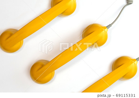 Pattern made from yellow color handset of a telephone on a white background. 69115331