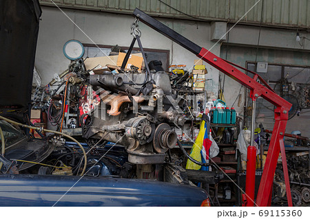 Engine hanging on crane hook on car repair service. Engine hanging on crane hook on car repair service. 69115360